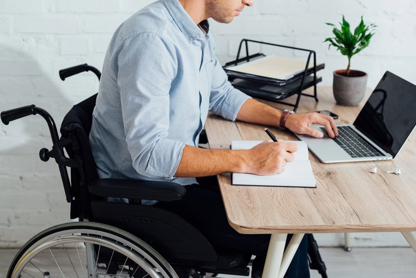 Mitarbeiter im Rollstuhl arbeitet produktiv am ergonomischen Arbeitsplatz